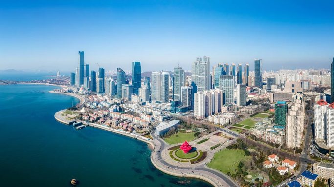 Aerial view of a coastal city skyline with modern skyscrapers and blue ocean.